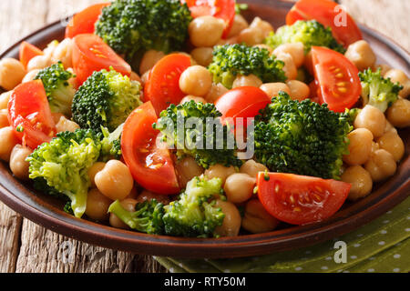 Insalata fresca di broccoli, ceci e pomodori conditi con olio di oliva close-up su una piastra sul tavolo. Posizione orizzontale Foto Stock