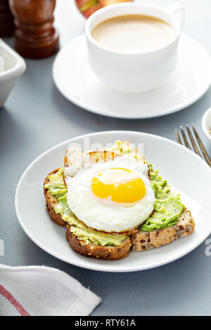 Avocado con toast fritti lato soleggiato in uovo Foto Stock