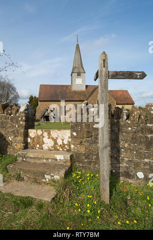 San Michele e Tutti gli Angeli, la chiesa parrocchiale del villaggio di Thursley nel Surrey, Regno Unito con il cartello per il modo Greensand lungo il percorso a distanza Foto Stock
