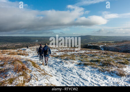 Gruppo di escursionisti a piedi al di sopra di Burley in Wharfedale villaggio su un snowy Burley/Ilkley Moor, West Yorkshire, Regno Unito Foto Stock