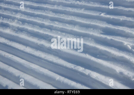 Linee di neve realizzata da una macchina di neve su una pista da sci Foto Stock