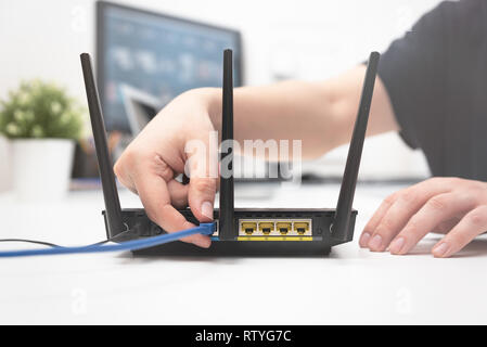 L uomo si connette il cavo internet al router di presa. Veloce e accesso wireless a internet concept Foto Stock