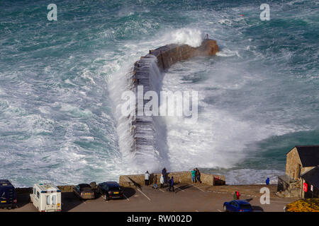 Sennen, Cornwall, Regno Unito. Il 3° marzo 2019. Gale force venti e 20ft di onde alte ancorare le scogliere di granito della Cornovaglia. Ponticelli audaci ottenere catturati da alcune enormi ondate di subissare la pier. Credito: Mike Newman/Alamy Live News. Foto Stock