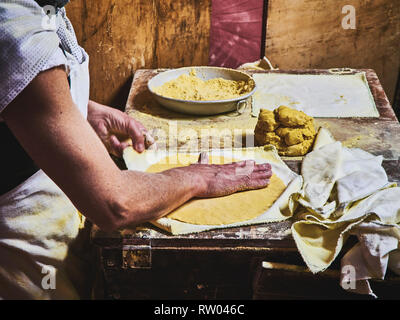 Un cuoco rendendo tortillas su una tavola di legno tavolo rustico. Foto Stock