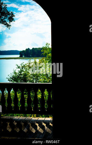 Vista della foresta paesaggio con un lago in una limpida giornata di sole attraverso la porta aperta di una casa con un antica terrazza. Foto Stock