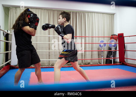 Un ragazzo e una ragazza kickbox fighters sparring nell'anello Foto Stock