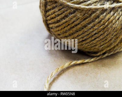 Iuta naturale rotolo di spago, vista dall'alto in bianco sullo sfondo di legno. DIY dono di avvolgimento della corda di canapa cavo bobina di stringa, forniture e strumenti per hobby fatti a mano di piacere. Foto Stock