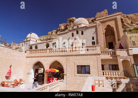 Mardin, Anatolia sud-orientale, la Turchia : un cameriere passeggiate presso la caffetteria all'aperto sull'edificio storico di il principale ufficio postale a destra sotto il xiv ce Foto Stock