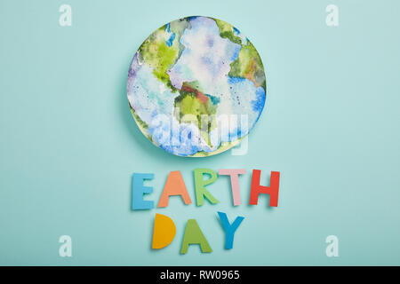 Vista superiore della carta colorata lettere e pianeta immagine sullo sfondo turchese, la giornata della terra concept Foto Stock