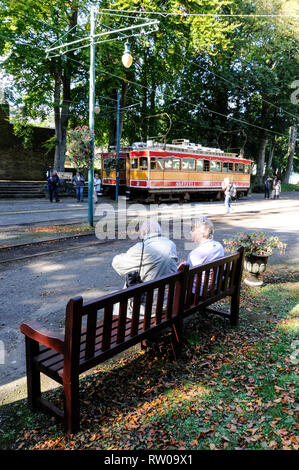 Una coppia di anziani la visione di due tram elettrico a Laxey Tram Terminus sulla 17 miglia lungo il binario il collegamento di Ramsey e Douglas sull'Isola di Foto Stock