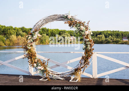 matrimonio arco rotondo in legno con fiori sul molo Foto stock - Alamy