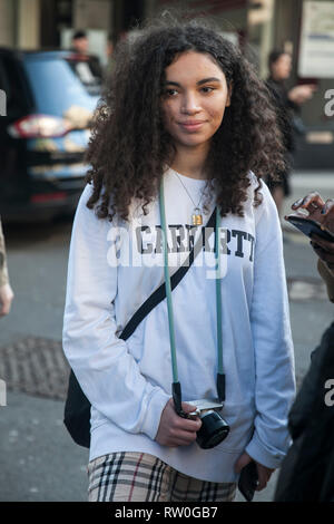 Londra - 15 febbraio 2019: Elegante partecipanti al di fuori di raccolta 180 del filamento per la London Fashion Week. Curly ragazza in una luce bianca e felpa pla Foto Stock