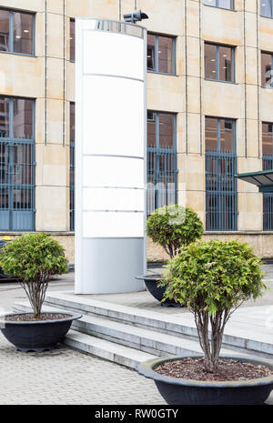 Grande vuoto verticale outdoor billboard con copia bianca spazio per aggiungere più nomi di società e loghi con ufficio moderno edificio in background Foto Stock
