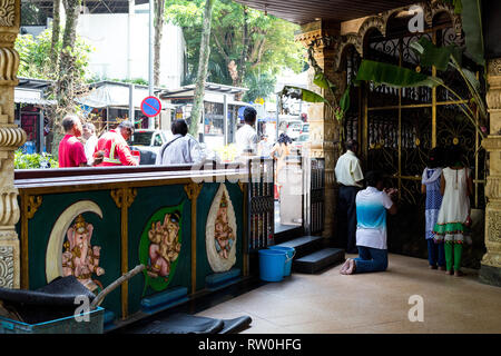 Corte Hill Ganesh tempio indù, Kuala Lumpur, Malesia. Adoratori guardando attraverso chiuso cancello di ingresso. Foto Stock