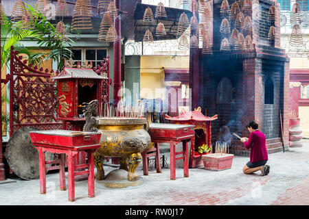 Peccato Sze Si Ya Tempio Taoista, Chinatown, Kuala Lumpur, Malesia. Adoratore inginocchiato con Joss (incenso) si inceppa nella parte anteriore del santuario. Foto Stock