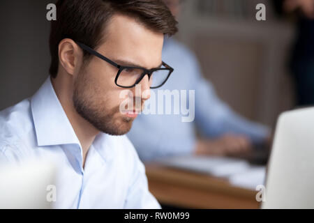 Close up ritratto giovane imprenditore cerca lavoro sullo schermo del computer Foto Stock