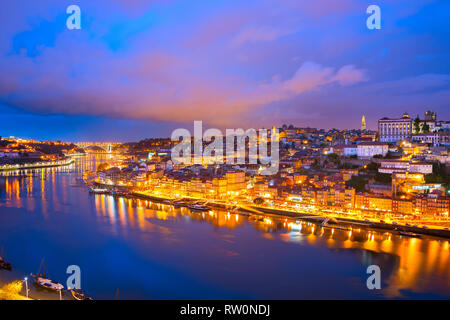 Colorate sullo skyline di post-incandescenza di porto illuminato città vecchia con le nuvole, riflettendo nel fiume Douro, Portogallo Foto Stock