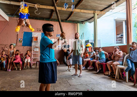 Giovane ragazzo latino swinging a pinata a Guatemala festa di compleanno Foto Stock