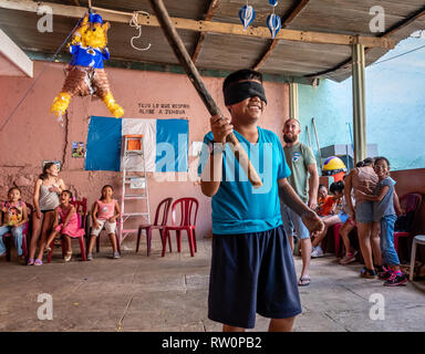 Giovane ragazzo latino swinging a pinata a Guatemala festa di compleanno Foto Stock