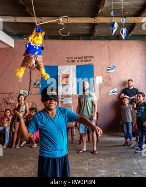 Giovane ragazzo latino swinging a pinata a Guatemala festa di compleanno Foto Stock