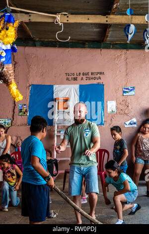 Giovane ragazzo latino swinging a pinata a Guatemala festa di compleanno Foto Stock