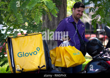 Lima in Perù - 3 Marzo 2019: Uomo sorridente con sacchetti Glovo lavorando alla consegna del cibo, servizio in piedi oltre il suo moto. Condivisione di economia collaborativa Foto Stock