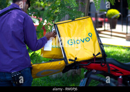 Lima in Perù - 3 Marzo 2019: uomo mettendo borse all'interno di una scatola di Glovo, alimentare il servizio di consegna. Condivisione di economia collaborativa concetto in Sud America. Foto Stock