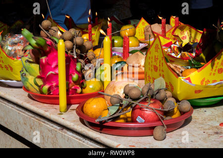 Cambogia, Phnom Penh, centro città, Wat Phnom, Neak Ta Preah Chao Santuario, candele accese tra le offerte di frutta Foto Stock