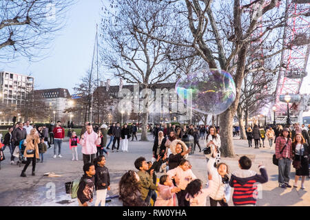 Busker,musicista di strada,a,enorme,palloncino,facendo,grande,bolla,bolle,per,i bambini,i bambini,a,gioco,South Bank,accanto,a,Fiume Tamigi,centro,d,Londra,l'Inghilterra,GB,UK, Foto Stock