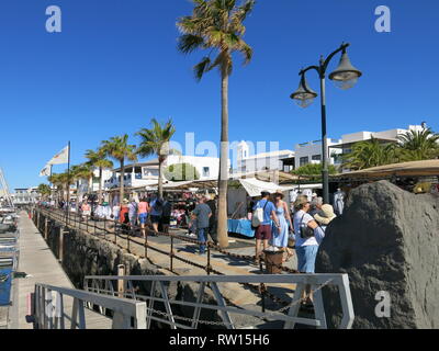La folla di turisti che affollano il mercoledì e il sabato mattina il coloratissimo mercato di strada al Rubicon Marina, Playa Blanca, Lanzarote; Febbraio 2019 Foto Stock
