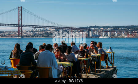 Lisbona, Portogallo - 2 Marzo 2019: le persone a rilassarsi nel ristorante sulla terrazza all'aperto che si affaccia sulla mitica 25 aprile ponte di Lisbona, Portogallo Foto Stock