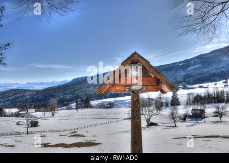 Kärnten Villach, Stadt, Panorama, Skyline, Stadt, Dobratsch, Wegkreuz, Holzkreuz, Baum, Wald, inverno, Schnee, Wiese, Weide, verschneit, kahl, AST, Äs Foto Stock