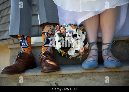 Sposa e lo sposo in piedi insieme che mostra le scarpe e calze e bouquet di fiori sul giorno di nozze Foto Stock
