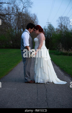 Sposa e lo Sposo che posano per una foto sul giorno di nozze all'aperto Foto Stock