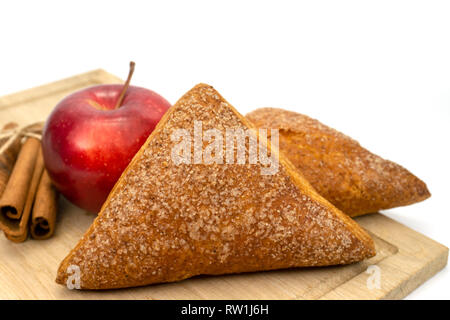 In casa di pasta sfoglia fatturati Apple, Apple e bastoncini di cannella su un tagliere di legno isolato su sfondo bianco Foto Stock
