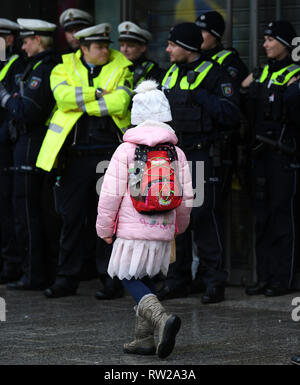 04 marzo 2019, della Renania settentrionale-Vestfalia, Düsseldorf: una forma dissimulata di ragazza cammina passato poliziotti durante il Martedì Grasso lunedì processione. Con la rosa lunedì processioni, Renania street carnival raggiunge il suo culmine. Foto: Ina Fassbender/dpa Foto Stock