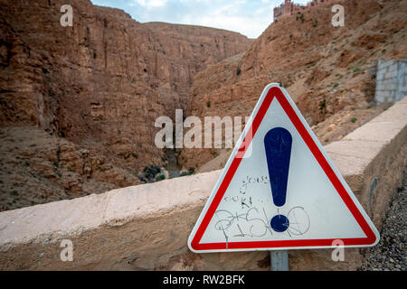 Un graffitied segnale di avvertimento in prossimità di un bordo di scogliera, Atlante, Ouzazate, Dades Gorge, Marocco. Foto Stock