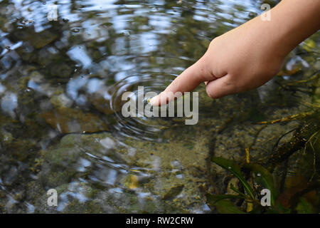 Close up dito tocca l'acqua e la goccia di acqua che cade e creazione di naturale e la calma delle forme d'onda,con calma concetto - Immagine Foto Stock