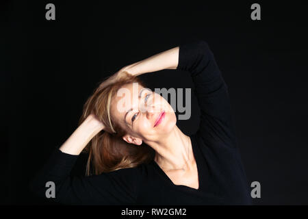 Close up studio ritratto di una bella donna in abito nero su sfondo nero Foto Stock