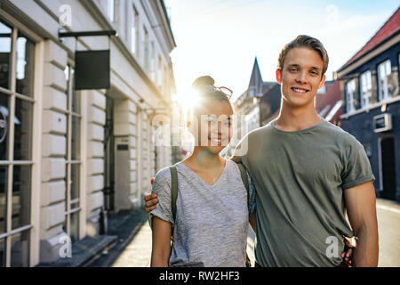 Coppia giovane in piedi insieme nella città e sorridente Foto Stock