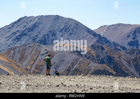 Mt Cheeseman, Canterbury, Nuova Zelanda, 2 Marzo 2019: un uomo con il suo cane, gode di una vista mozzafiato sulla valle Foto Stock