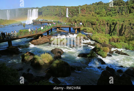 Grande gruppo di visitatori sul lungomare tra il potente flusso, Iguazu Falls a lato Brasiliano, di Foz do Iguacu, Brasile, Sud America Foto Stock