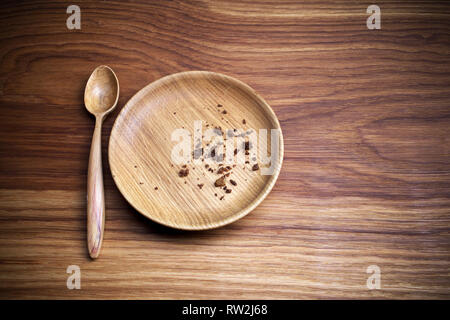 Il digiuno quaresimale. Piastra con cucchiaio e mollica su sfondo di legno Foto Stock