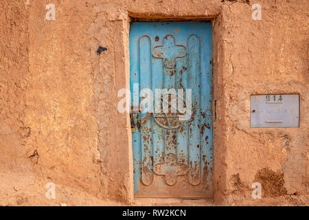 Esterno dei tradizionali mattoni di fango edificio costruito con lo sportello blu con pentacolo, trovati in Marocco bandiera, oasi di Tighmert, Marocco Foto Stock