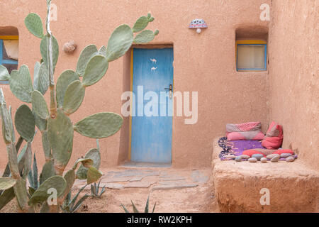 Esterno di mattoni di fango casa costruita con porta blu e cactus di fronte, oasi di Tighmert, Marocco Foto Stock