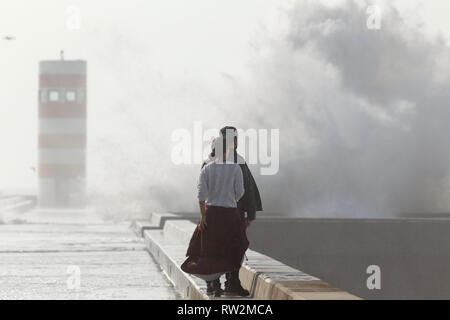 Porto, Portogallo - 2 Febbraio 2016: guardare la gente violenta mareggiata di onde che si infrangono contro il molo sud del fiume Douro bocca. Foto Stock