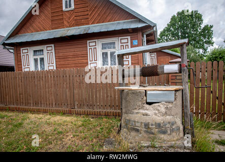 Acqua siede ben coperta in cantiere con cabina-casa in stile decorativo con otturatori dietro di esso in Trześcianka "Terra di persiane aperte", POLONIA, Foto Stock