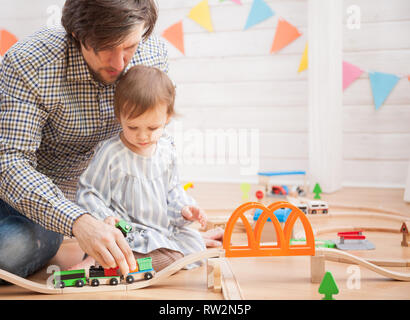 Carino bambina e suo padre a giocare con la ferrovia giocattolo road Foto Stock