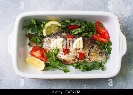 Carpa al forno pesce con spezie e verdure in una teglia da forno Foto Stock