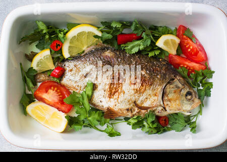 Carpa al forno pesce con spezie e verdure in una teglia da forno Foto Stock